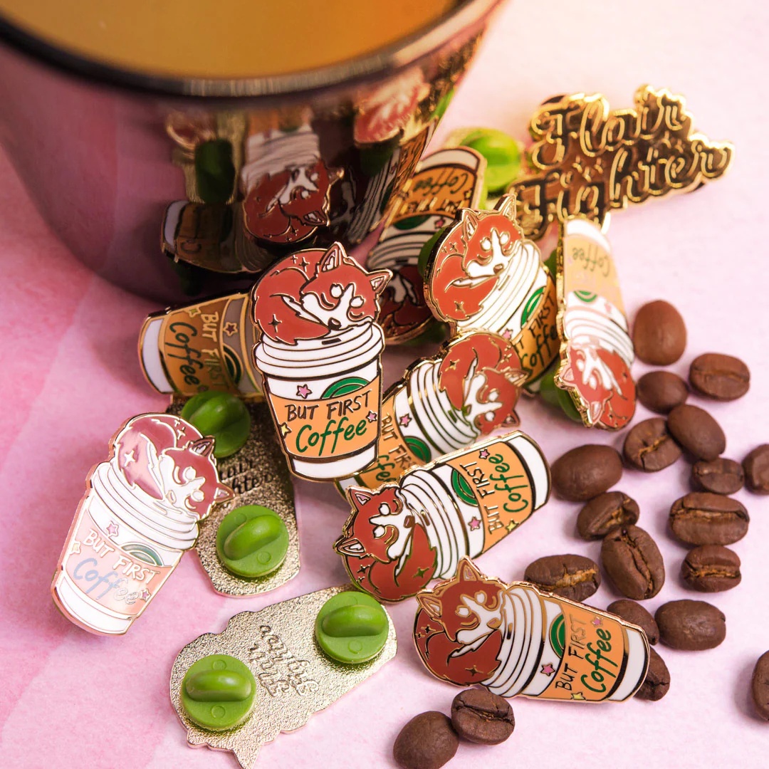 A set of coffee-themed enamel pins featuring a fox design
