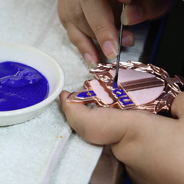 Detailed process of applying cloisonne enamel to a copper medallion.