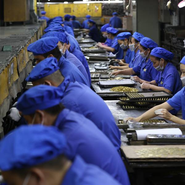 Workers on the assembly line performing hand polishing on metal products.