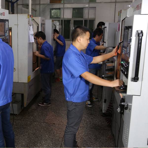 Factory workers operating CNC machinery for mold carving.