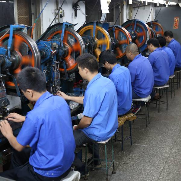 Industrial workers operating a punching machine in the factory.