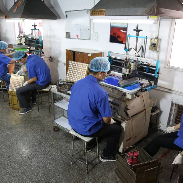 Factory workers operating silkscreen printing machinery.