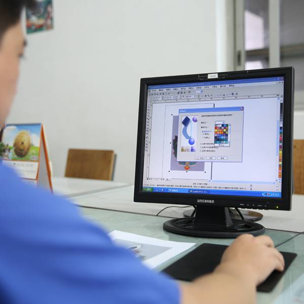 A person working on a computer, using graphic design software for artwork preparation.