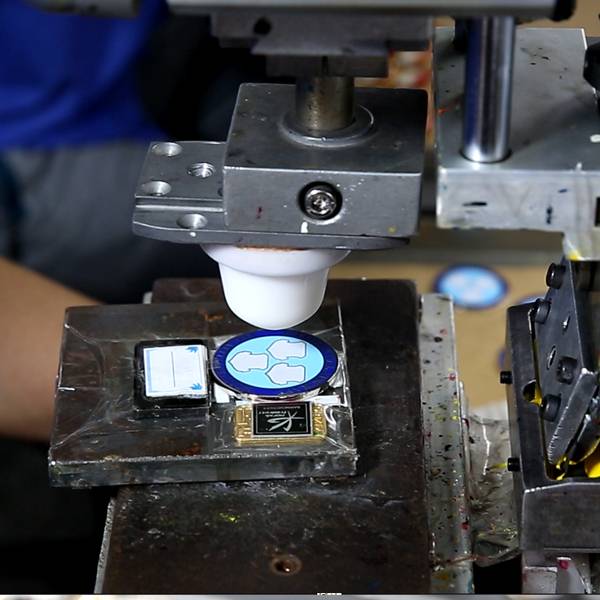 An industrial machine performing pad printing on components.