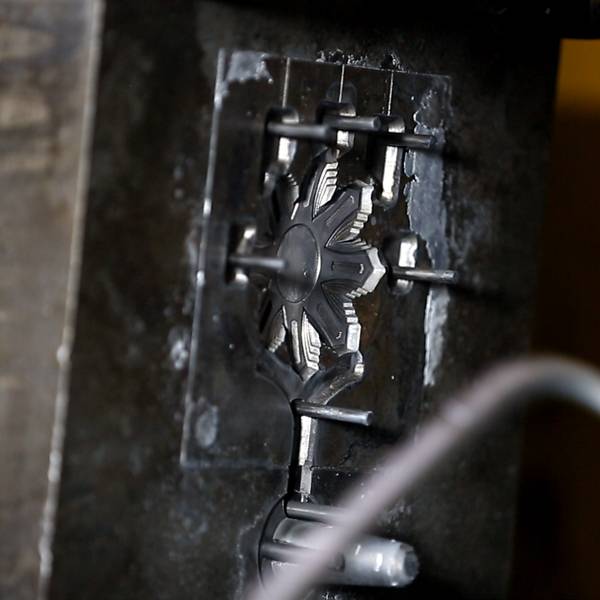 A freshly die-casted metal object with an intricate floral design.