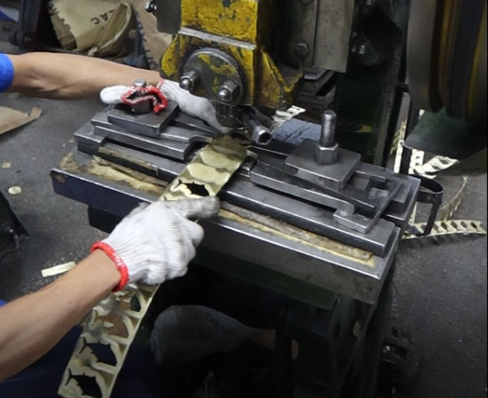A metalworking machine in operation, cutting the external shape of a stamped emblem.