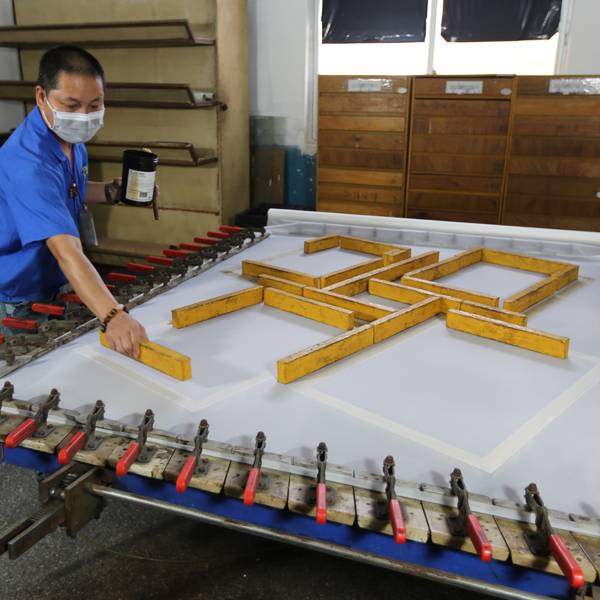 A worker preparing a frame for the screen printing process.