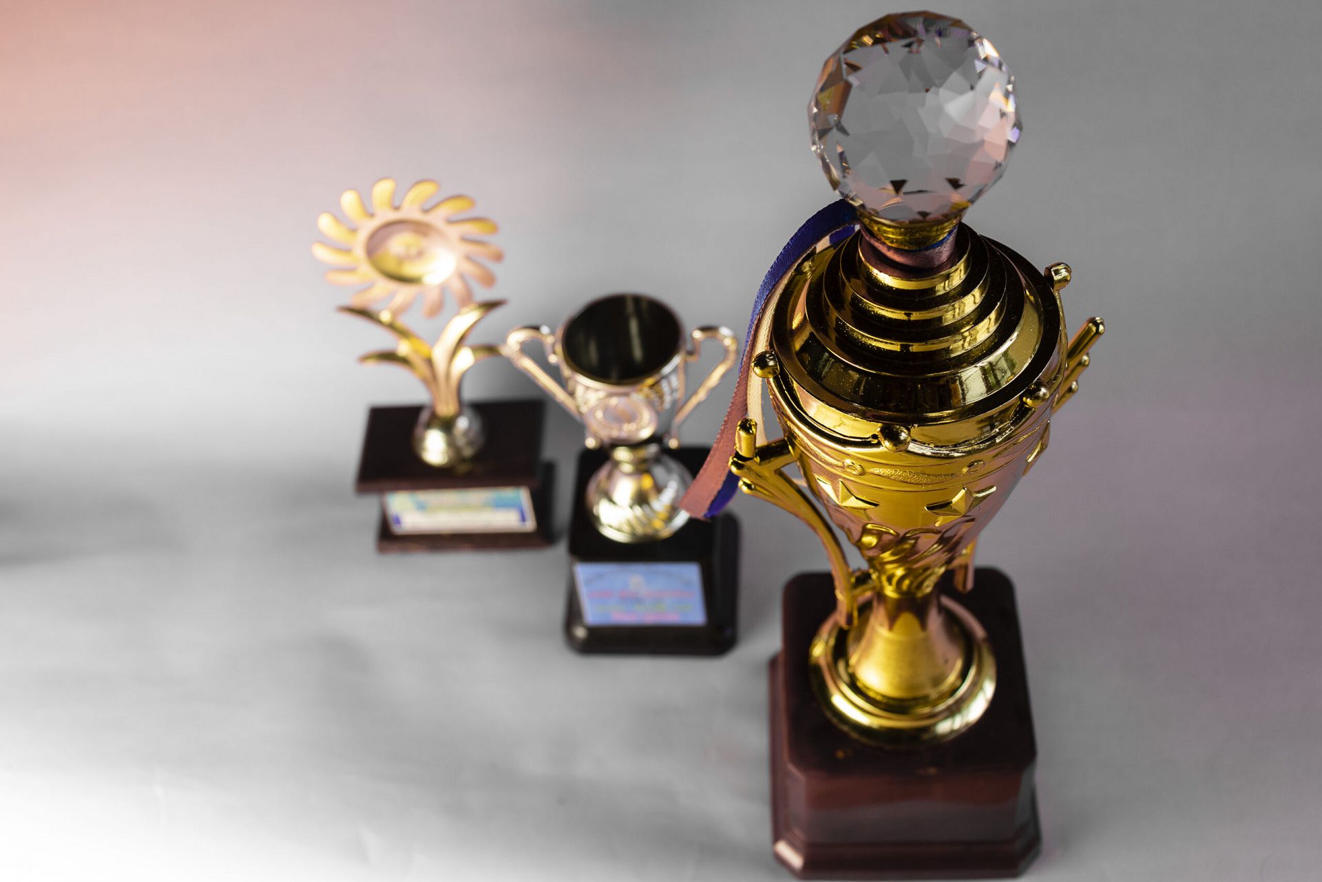 A collection of three distinct golden trophies for awards.